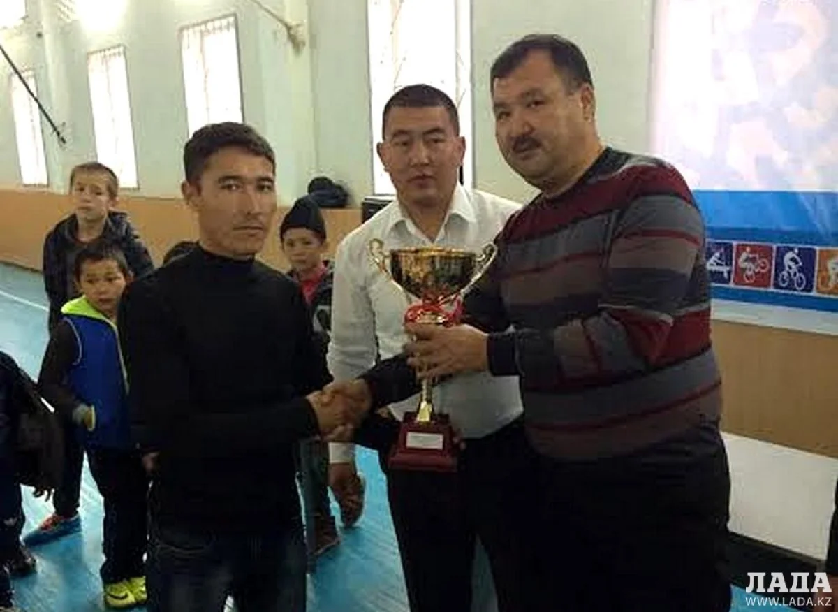 Заместитель акима села Баскудук Мурат Жумабаев вручает кубок тренеру школы №6 села Кызылтобе-2 Пердебеку Кашкамбаеву