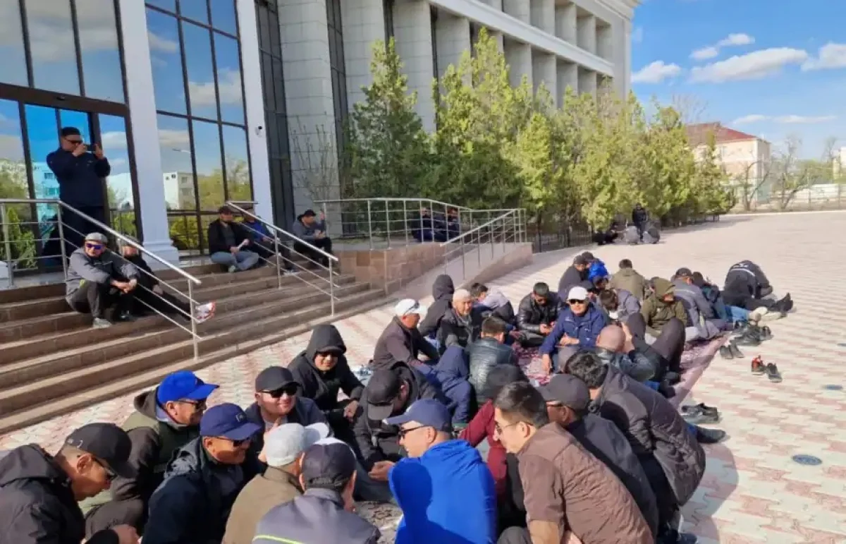 Рабочие, требующие трудоустройство, сидят перед офисом предприятия «Озенмунайгаз». Жанаозен, 4 апреля 2023 года