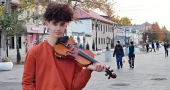 Подросток одновременно катается на скейте и играет на скрипке в ВКО
