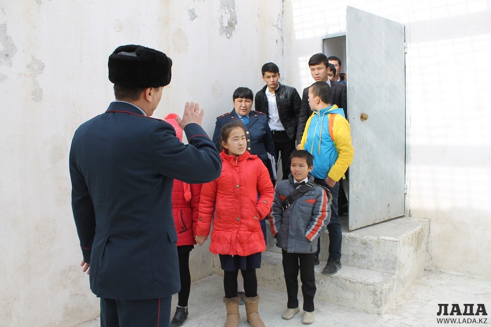 Полицейский показывает детям дворик, где прогуливаются административно арестованные граждане. Фото автора