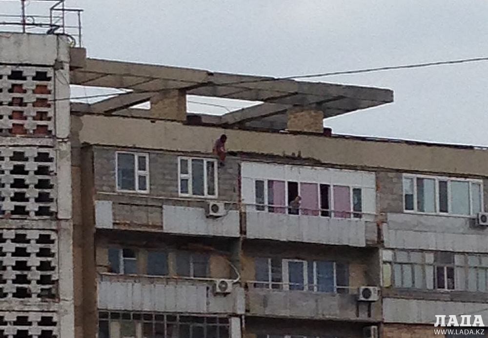 Женщина сидит на краю крыши многоэтажного дома. Фото очевидцев.
